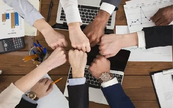 Hình ảnh mọi người làm việc chấp tay nhau thể hiện đoàn kết.