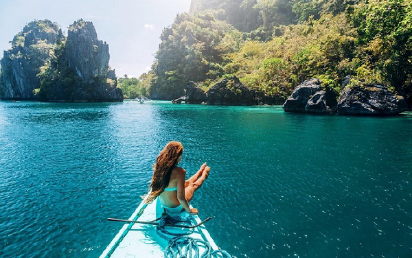 Hình ảnh cô gái đang ngồi ở mũi thuyền tận hưởng vẻ đẹp ở bãi biển Philippines